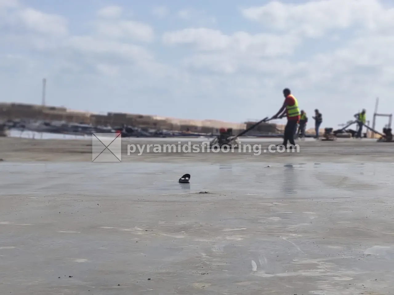 عامل يشغّل ماكينة هليكوبتر لتنعيم سطح بلاطة خرسانية